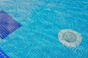Cleaning of the drain valve filter at the bottom of the swimming pool, movement of clear water, top view.