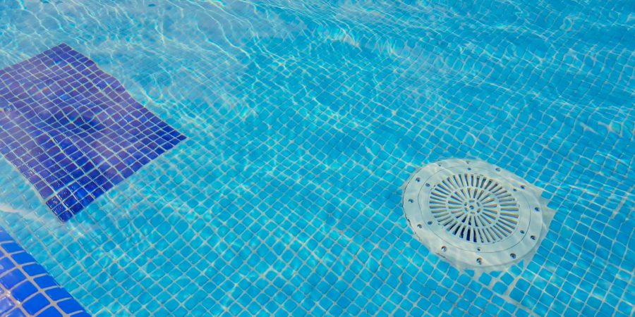 Cleaning of the drain valve filter at the bottom of the swimming pool, movement of clear water, top view.